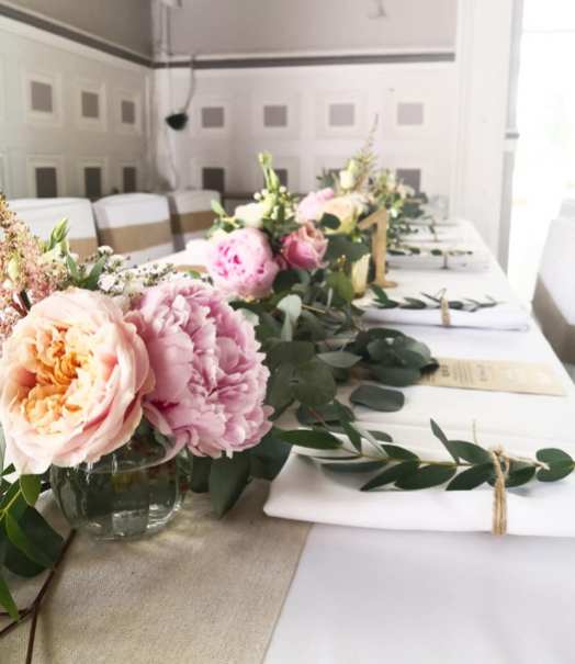 Centre de table de table d'honneur avec guirlande d'eucalyptus et bouquets pastel